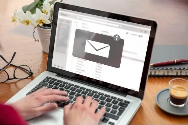 A laptop on a desk showing an inbox with one new email waiting